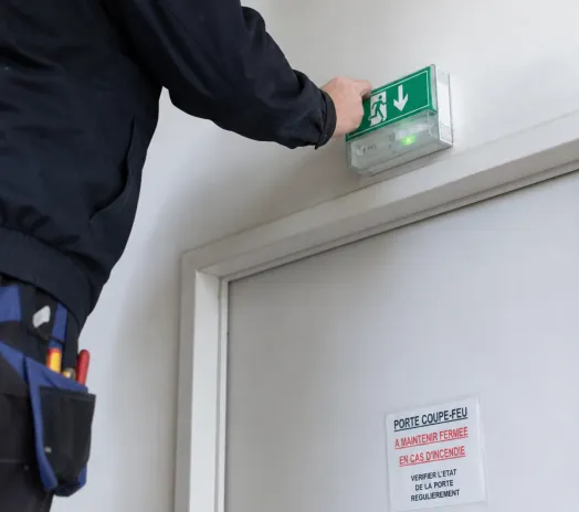 Technicien SR2i contrôlant un bloc de secours BAES